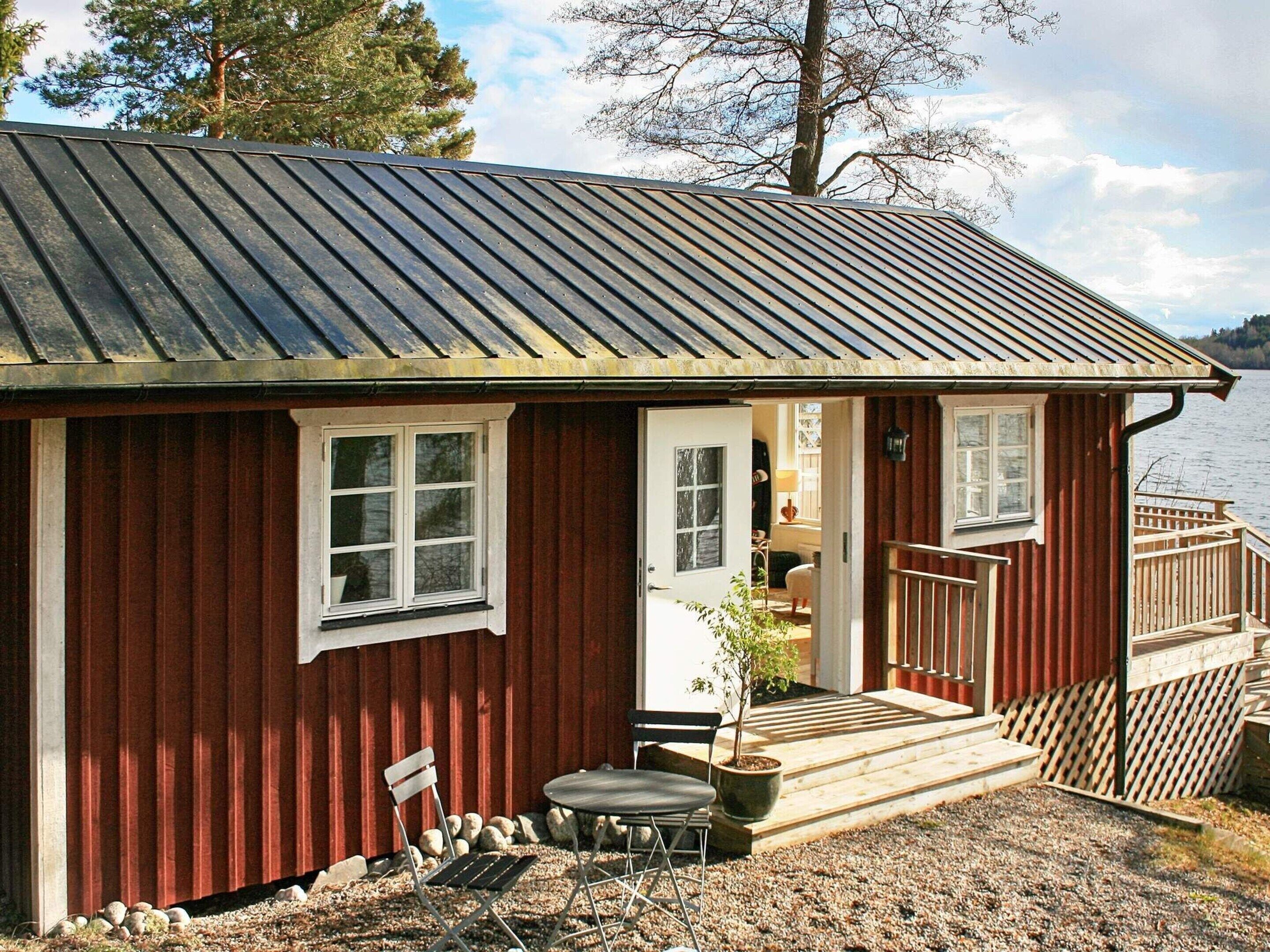 Une petite cabane en bois avec un toit en métal, une terrasse en bois et un petit espace patio avec une table et des chaises.