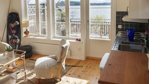 A cozy kitchen with large windows overlooking a lake, a dining area with a chair and table, and a view of the outside deck. - 4 Person Holiday Home in Farentuna (Faerentuna)