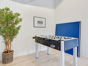 A room with a foosball table, a framed picture on the wall, and a potted plant.