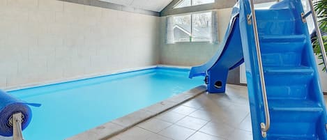 Una piscina interior con un tobogán azul y una escalera.