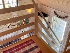 A wooden staircase with a railing, a chandelier, and a patterned rug. - 4 Star Holiday Home in Ellos (Ellos)
