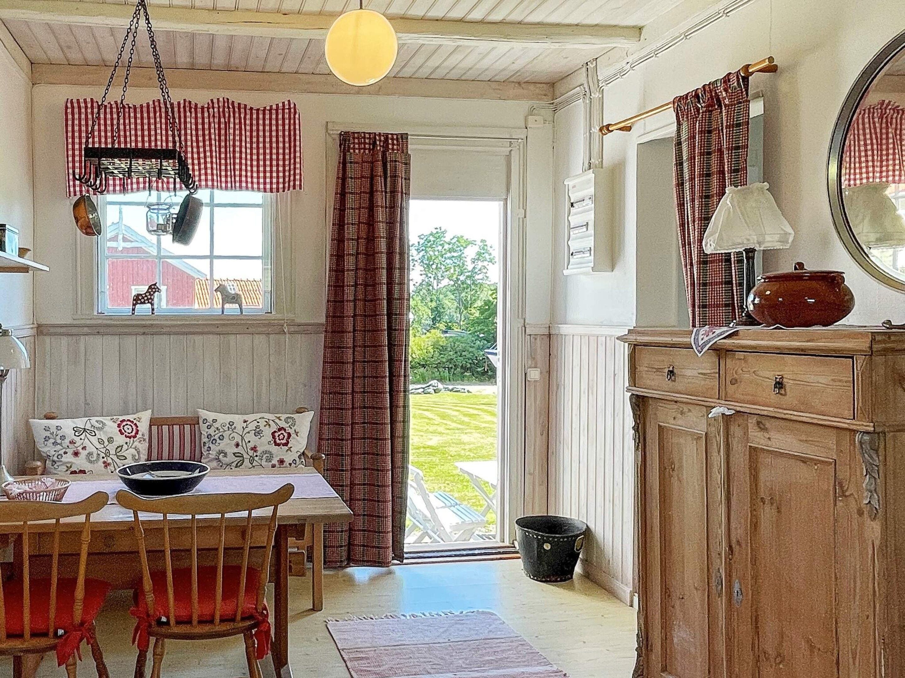 A cozy kitchen with a dining table, chairs, a hanging light fixture, and a view through a window.