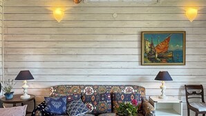 A cozy room with a patterned sofa, a small round table, a potted plant, and a painting on the wall. - 4 Star Holiday Home in Ellos (Ellos)