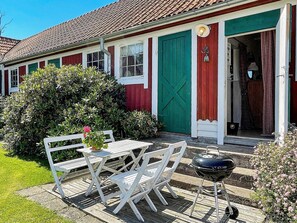 A red and white building with a green door, a bench, and a barbecue grill in the foreground. - 4 Star Holiday Home in Ellos (Ellos)