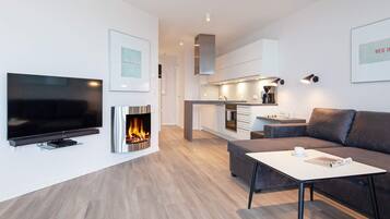 A modern living room with a flat-screen TV, a fireplace, a sofa, and a coffee table.