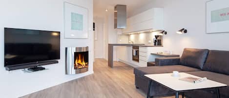 A modern living room with a flat-screen TV, a fireplace, a sofa, and a coffee table.