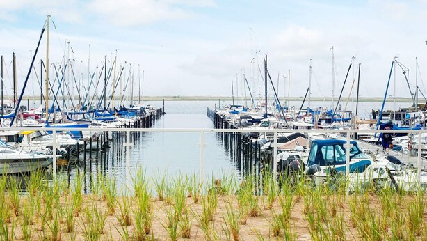 A marina with boats docked, surrounded by sand and grass. - 5 Star Holiday Home in Wendtorf (Wendtorf)