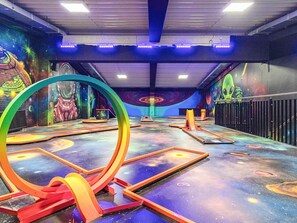 Espaço de recreação infantil com murais coloridos, uma grande estrutura circular e diversos equipamentos de brincadeira.