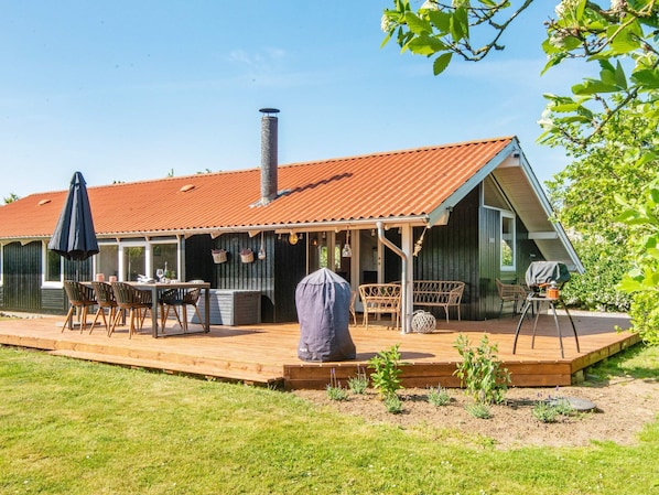 Una casa con porche cubierto, mobiliario exterior y chimenea.