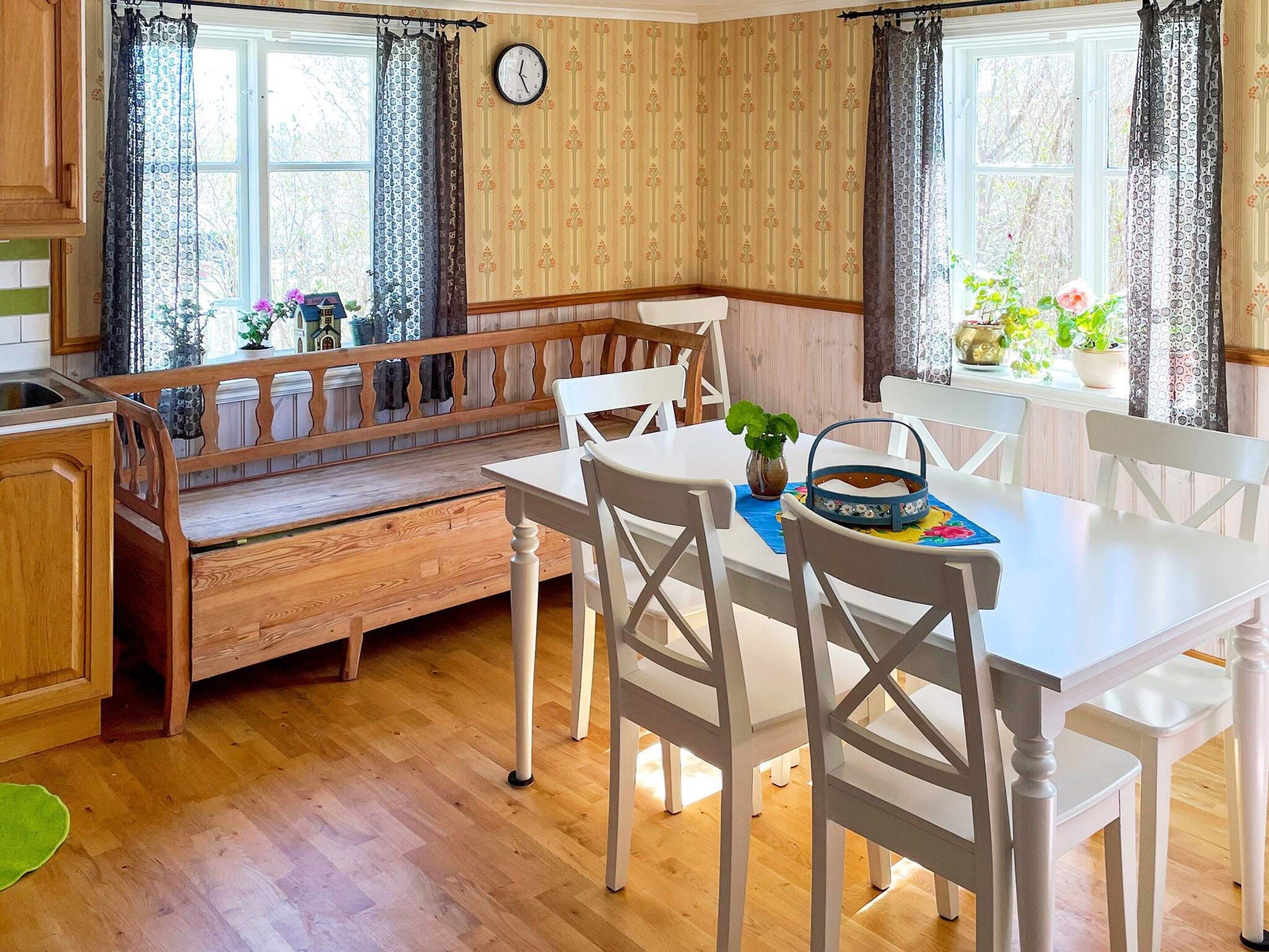 Een gezellige keuken met houten kastjes, een bankje en een eettafel met stoelen.