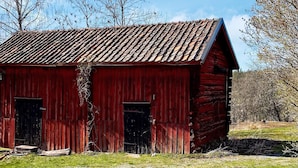 A red wooden barn with two doors and a sloped roof. - 4 Person Holiday Home in Arboga (Arboga)