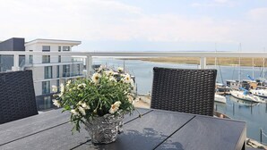 A balcony with a table, chairs, and a flower vase with white flowers. - 5 Star Holiday Home in Wendtorf (Lubeck)
