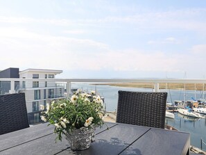 A balcony with a table, chairs, and a flower vase with white flowers. - 5 Star Holiday Home in Wendtorf (Lubeck)