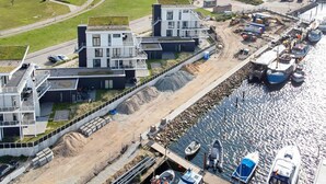 An aerial view of a coastal area with modern buildings, a marina with boats, and a curved road. - 5 Star Holiday Home in Wendtorf (Lubeck)