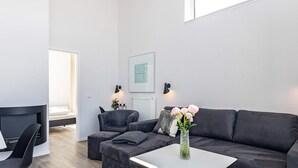 A modern living room with a sofa, armchair, and ottoman, a small table, and a vase with flowers. - 5 Star Holiday Home in Wendtorf (Lubeck)