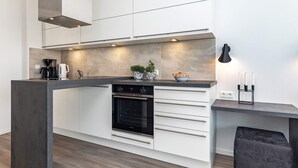 A modern kitchen with a built-in oven, a coffee maker, and a small potted plant.