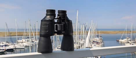 Une paire de jumelles posée sur une rambarde, donnant sur une marina où sont amarrés de nombreux bateaux.