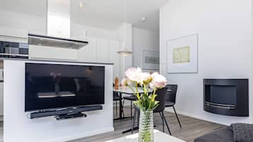 En moderne stue med et fladskærms-tv, et spiseområde og en pejs.