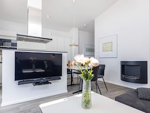 Ein modernes Wohnzimmer mit einem Flachbildfernseher, einem Essbereich und einem Kamin.