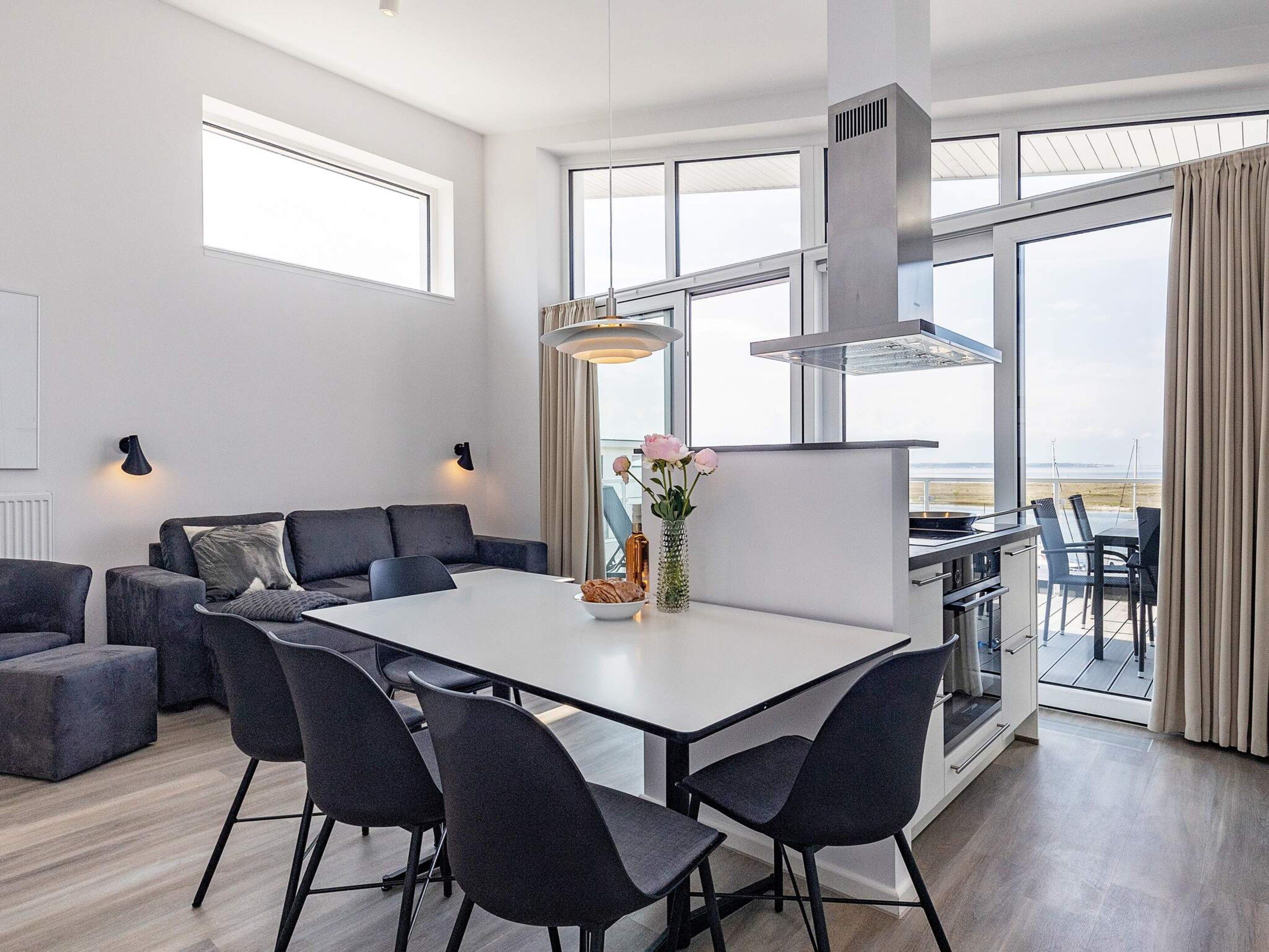 Een moderne woonkamer met een eethoek, grote ramen en uitzicht op het landschap.