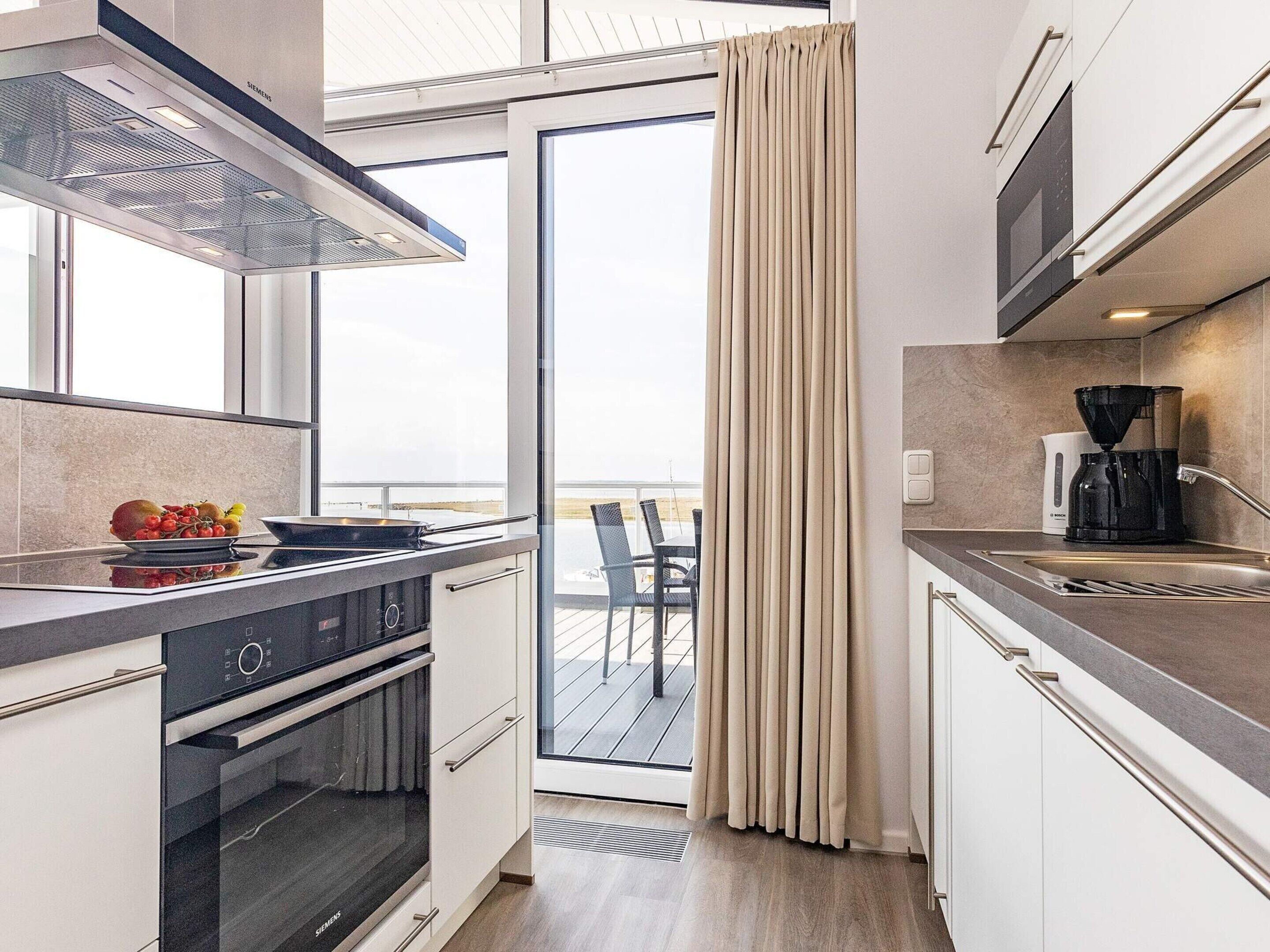 Una cocina moderna con horno integrado, cafetera y vistas al exterior.