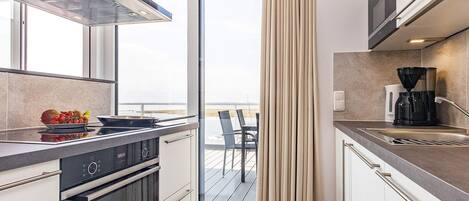 Una cocina moderna con horno integrado, cafetera y vistas al exterior.