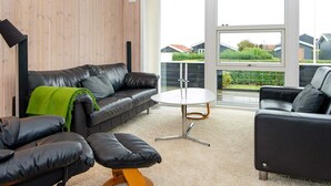 Una sala de estar moderna con un sofá de cuero, una mesa de centro redonda y un sillón negro.