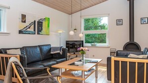 Uma sala de estar moderna com sofá de couro preto, mesa de centro de madeira e lareira.