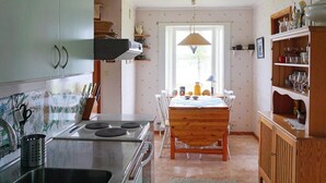 A kitchen with a stove, dining table, chairs, and a window. - 6 Person Holiday Home in Holsljunga (Holsljunga)