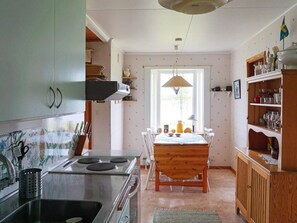 A kitchen with a stove, dining table, chairs, and a window. - 6 Person Holiday Home in Holsljunga (Holsljunga)