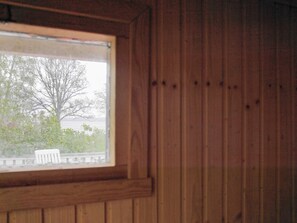 A wooden paneled wall with a window overlooking a balcony with a chair. - 6 Person Holiday Home in Holsljunga (Holsljunga)