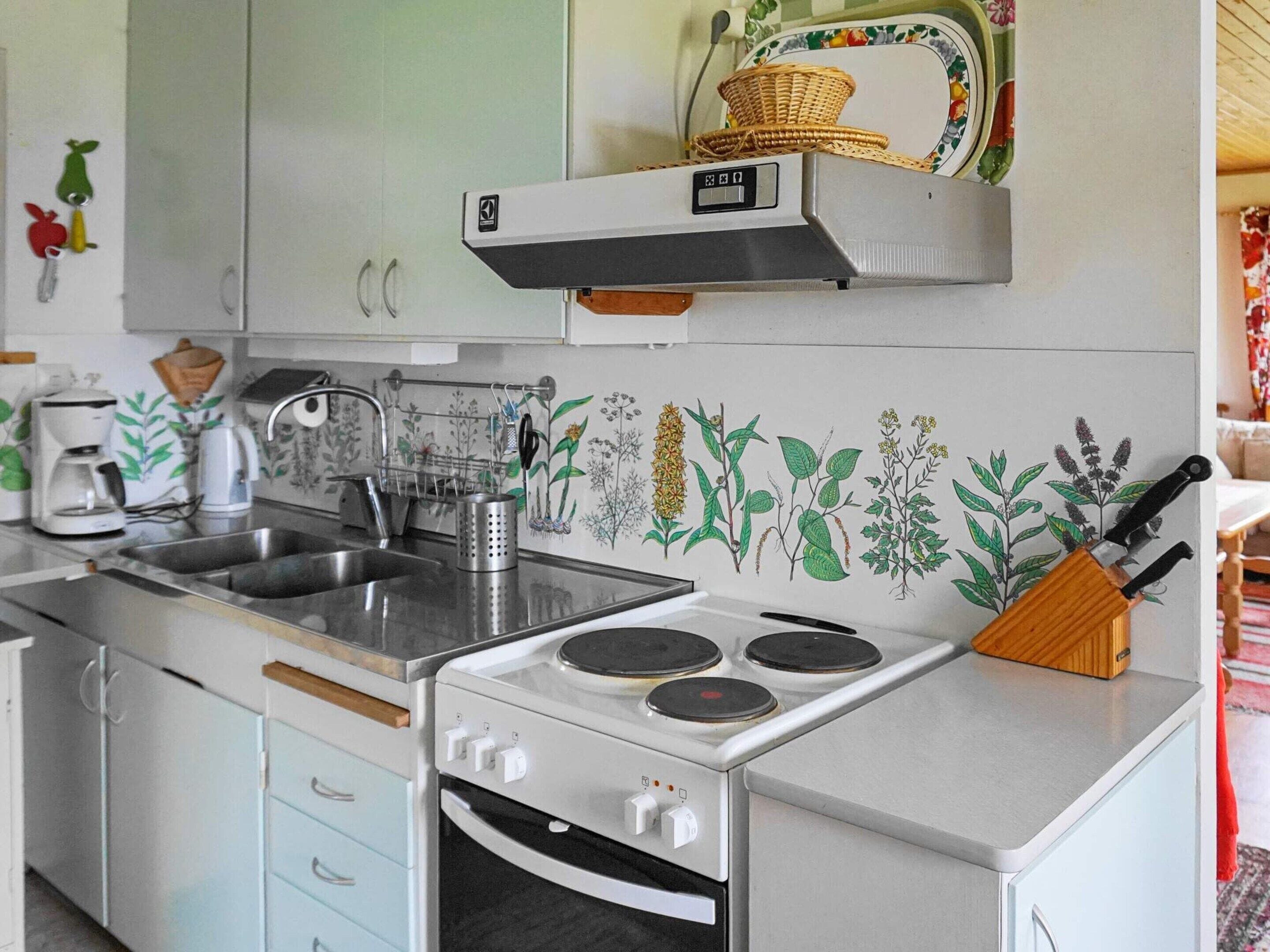 Une cuisine compacte équipée d’un évier, d’une cuisinière et d’un étagère fixée au mur.