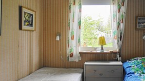 A small room with a single bed, a nightstand with drawers, a lamp, and a window with curtains. - 6 Person Holiday Home in Holsljunga (Holsljunga)