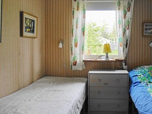 A small room with a single bed, a nightstand with drawers, a lamp, and a window with curtains. - 6 Person Holiday Home in Holsljunga (Holsljunga)