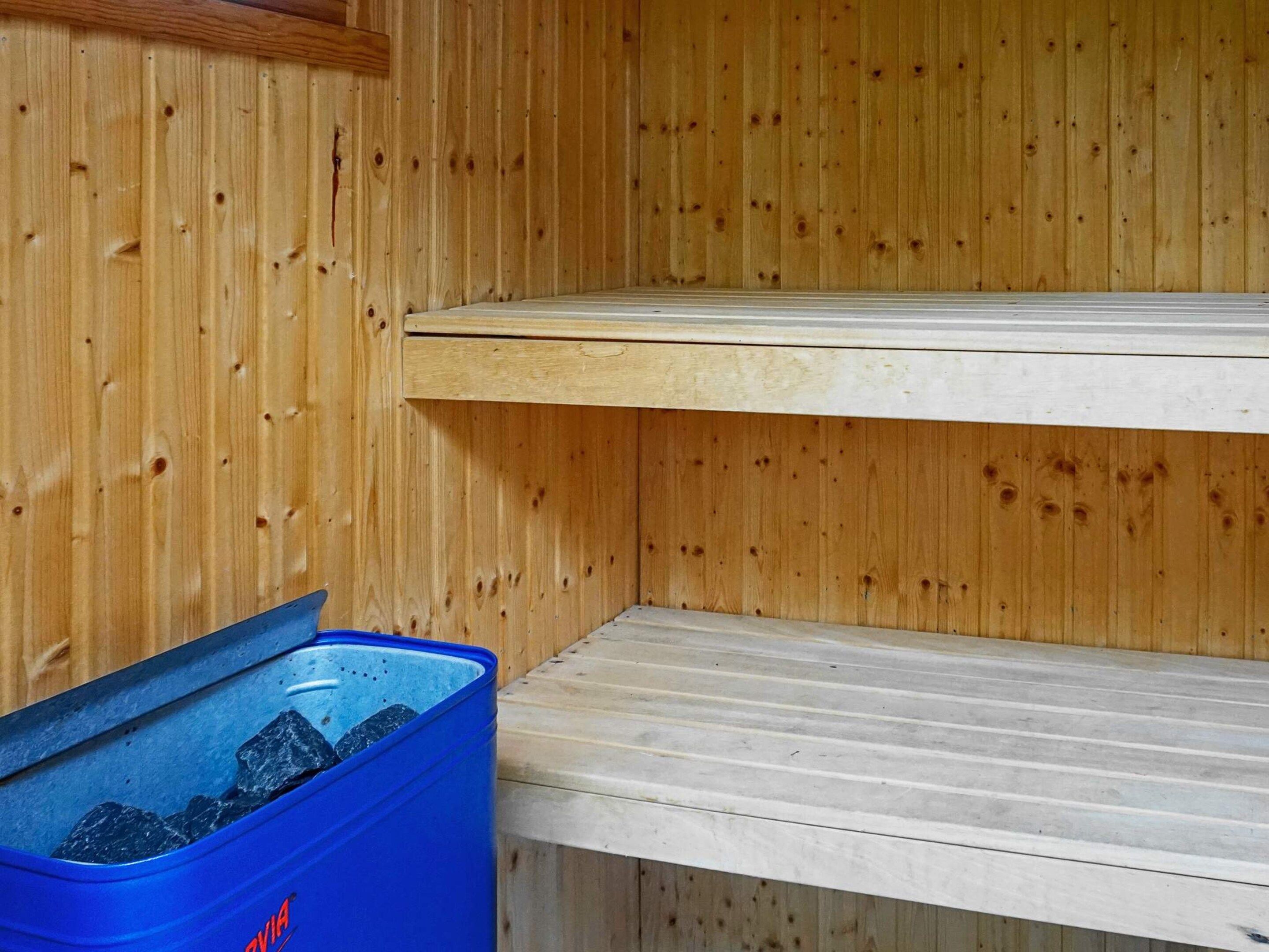 A wooden interior with a blue trash bin and a white shelf.