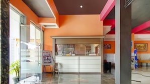 Um hall de hotel com balcão de recepção, porta de vidro e piso ladrilhado.