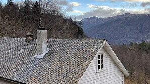 A white house with a stone roof, a chimney, and a view of mountains. - 8 Person Holiday Home in Akra-by Traum (Kvinnherad)