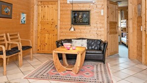 Ein gemütlicher Holzraum mit einer Couch, Sesseln, einem Tisch und einem Teppich.