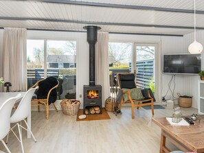 Cozy living room with a central stove, large window, and flat-screen TV.