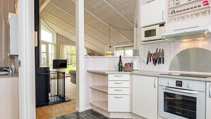 Ett modernt kök med vita köksskåp, en inbyggd ugn och en mikrovågsugn.