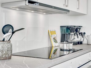 Cozinha moderna com fogão embutido, máquina de café e chaleira.