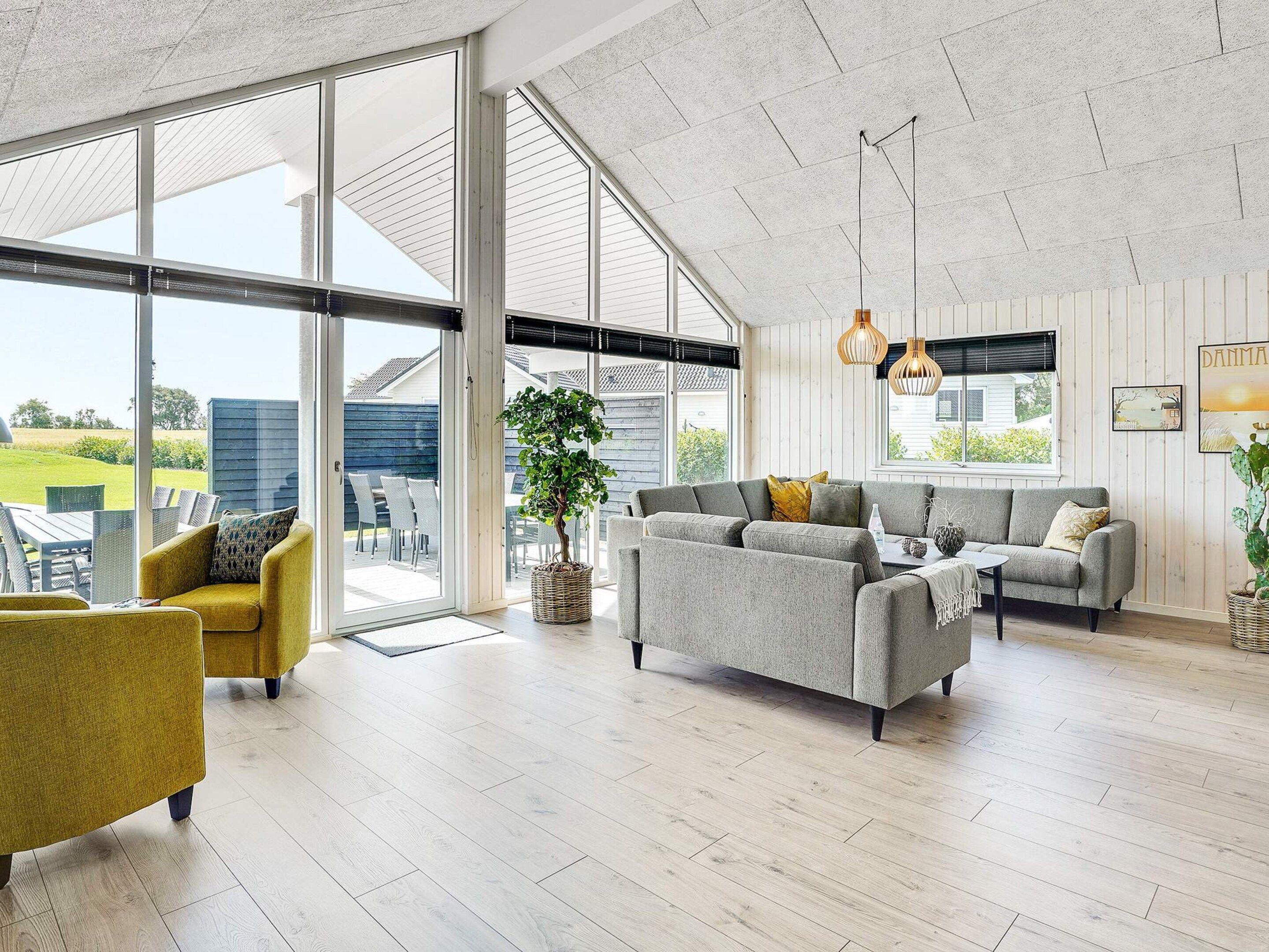 A spacious living area with a large sliding glass door leading to an outdoor patio, a grey sofa set, and a yellow armchair.