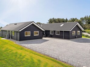 Een gebouw met twee verdiepingen, een grindpad en een gazon ervoor.