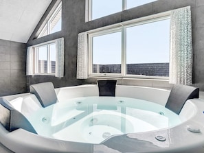 A modern bathroom with a freestanding bathtub, large windows, and a view of the cityscape.