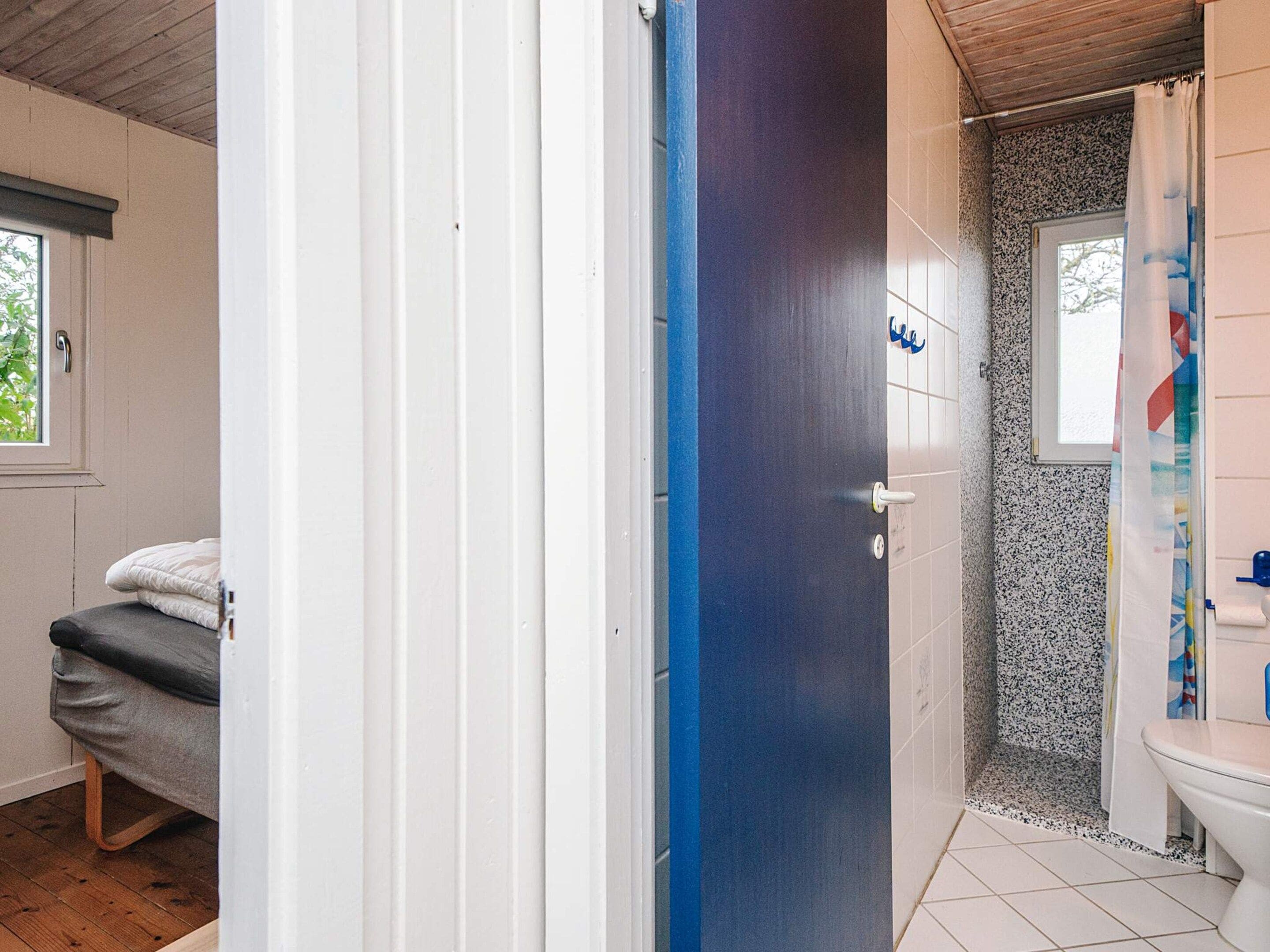 A bathroom with a shower, toilet, and a window.