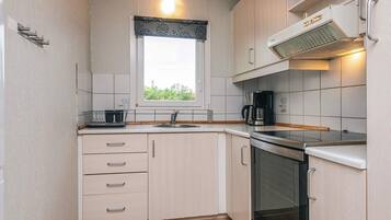 A compact kitchen with a window, a coffee maker, and a stove.
