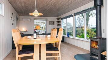 A cozy dining area with a wooden table and chairs, a hanging light fixture, and a large window with a view of the outdoors.