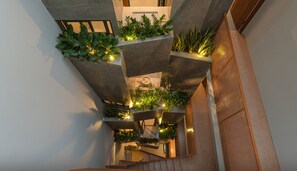 A multi-level interior with concrete pillars supporting greenery and a central staircase. - Shelter Stay Da Nang (Da Nang)
