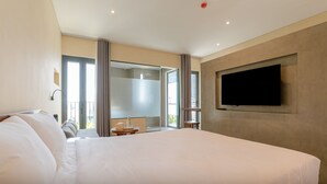 A modern hotel room with a large bed, a television mounted on the wall, and a balcony with a sliding door. - Shelter Stay Da Nang (Da Nang)