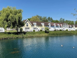 Een rij gele huizen met een vijver op de voorgrond.